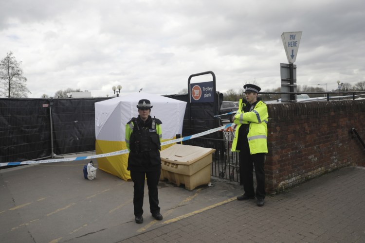FILE - In this March 13, 2018, file photo, Police officers guard a police tent covering a supermarket car park pay machine near the spot where former Russian spy Sergei Skripal and his daughter were found critically ill following exposure to the Russian-developed nerve agent Novichok in Salisbury, England, in March. The United States will impose sanctions on Russia for the country's use of a nerve agent in the assassination attempt on the Skripals.