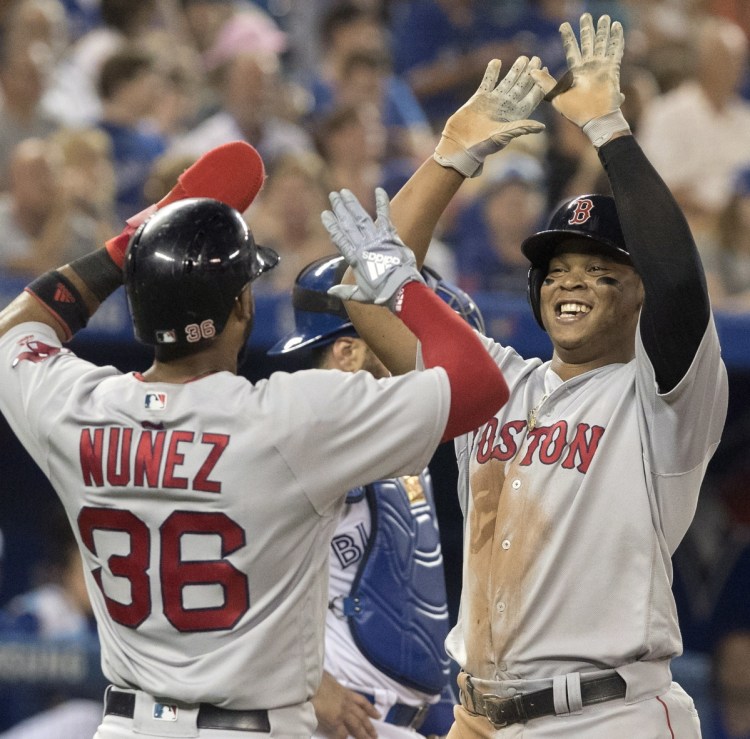 Rafael Devers gets a welcome-home high-five from Eduardo Nunez after hitting a two-run homer in the sixth inning Wednesday night in Toronto.