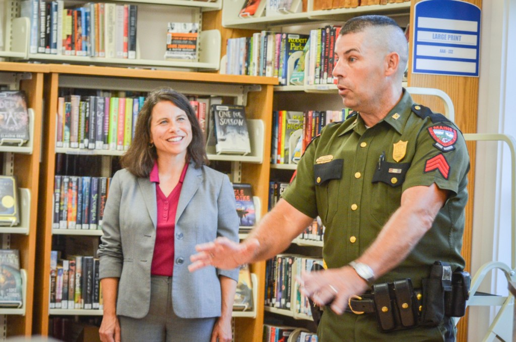 District Attorney Meaghan Maloney listens as Maine game warden Sgt. Terry Hughes describes the night he arrested the North Pond Hermit to a crowd at the Belgrade Public Library.