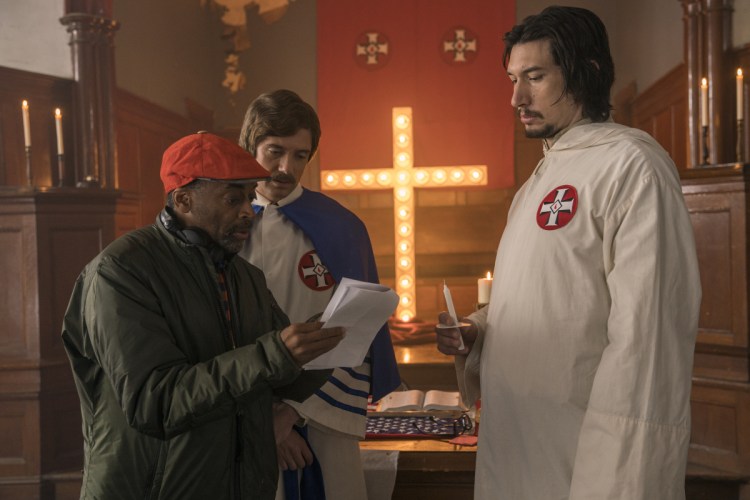 This image released by Focus Features shows director Spike Lee, left, with actors Topher Grace, center, and Adam Driver on the set of Lee's film "BlacKkKlansman." Lee is releasing his film this weekend, a year after the violent clashes in Charlottesville in which anti-racism activist Heather Heyer was run over and killed. Lee‚Äôs film is about an earlier chapter in white supremacism and the Ku Klux Klan: when African-American police detective Ron Stallworth infiltrated a Colorado Springs, Colorado, chapter of the KKK in 1979. 