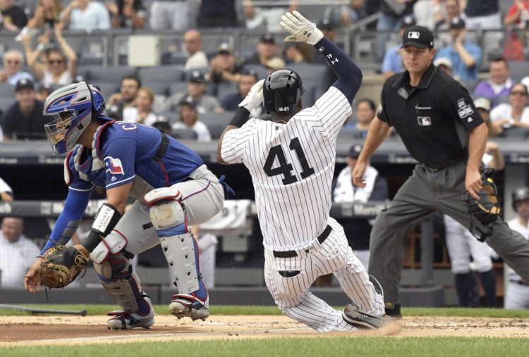 Miguel Andujar of the New York Yankees scores on a double by Greg Bird as Texas catcher Robinson Chirinos waits for the ball Saturday. The Yankees won, 5-3.