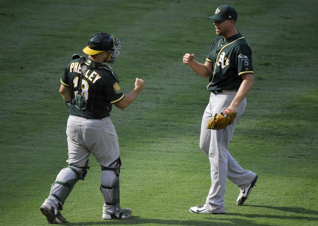 Oakland Athletics catcher Josh Phegley, left, and relief pitcher Blake Treinen congratulate each other after another victory. The A's have risen to offer a challenge to Houston and Seattle in the AL West.