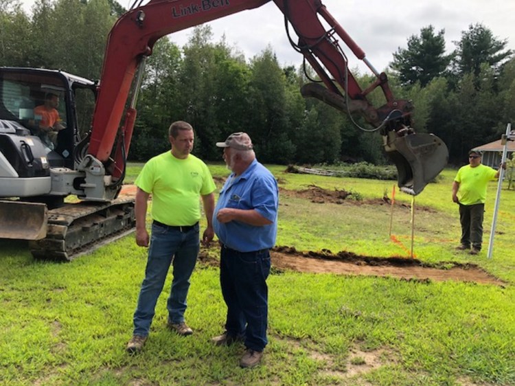 Mickey Wing, right, of Central Maine Disposal and Excavation, confers with Joel Violette, of Fairfield Drafting & Construction, about plans for a new home for Sheryl Cole.