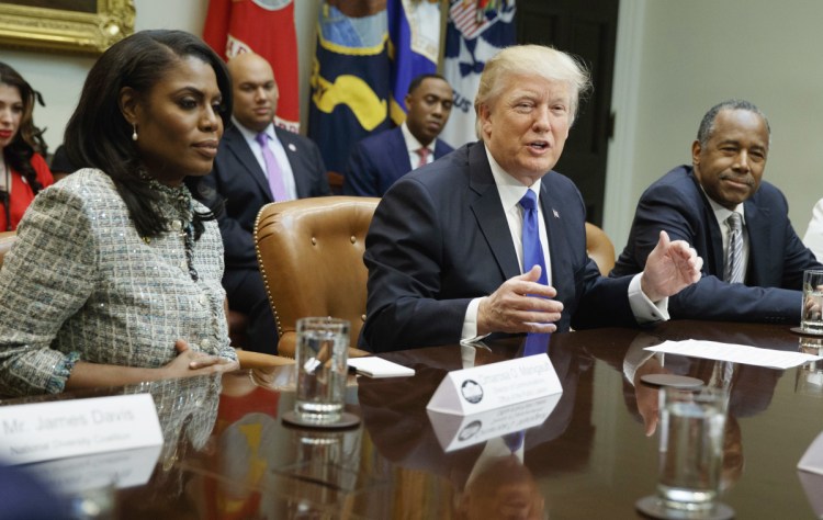 President Trump is flanked by White House staffer Omarosa Manigault Newman, left, and  then-Housing and Urban Development Secretary-designate Ben Carson as he speaks during a meeting on African American History Month in the Roosevelt Room of the White House in Washington. Manigault Newman, who was fired in December, released a new book "Unhinged," about her time in the White House.