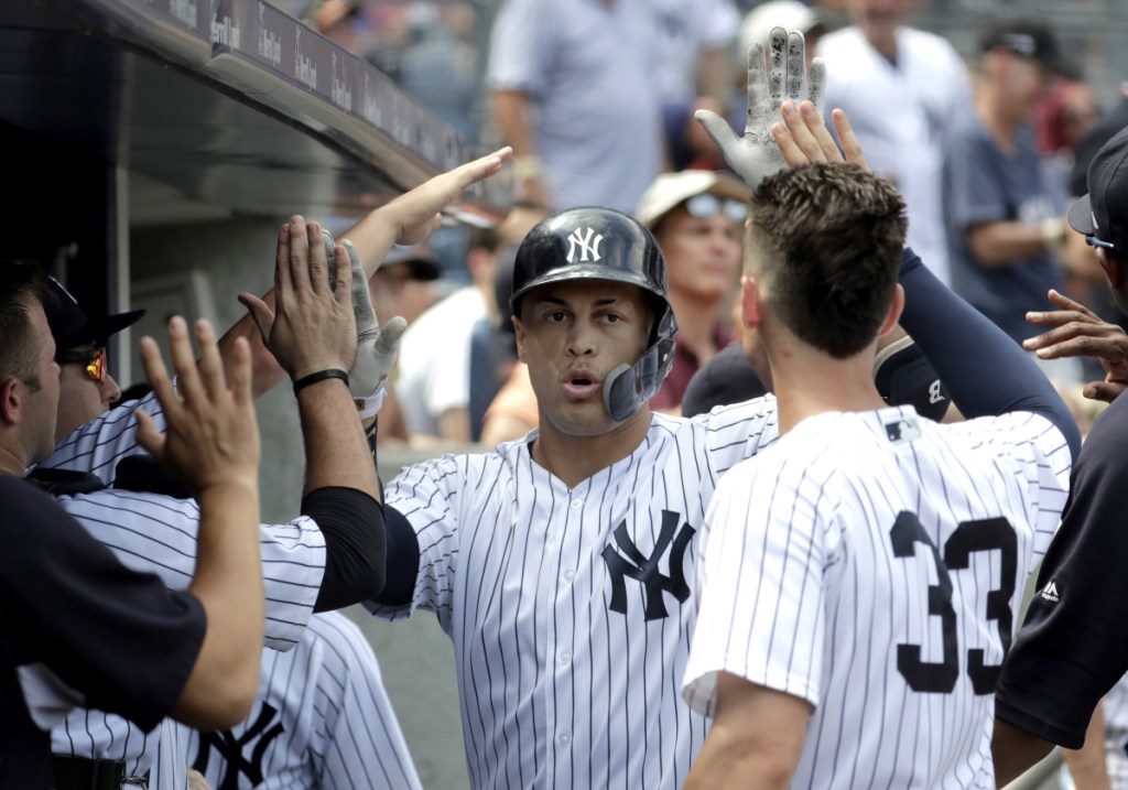 Giancarlo Stanton of the New York Yankees, center, is congratulated by teammates Saturday after hitting a solo home run in the fourth inning of an 11-6 victory against the Toronto Blue Jays. Stanton has seven homers in his last 12 games.
