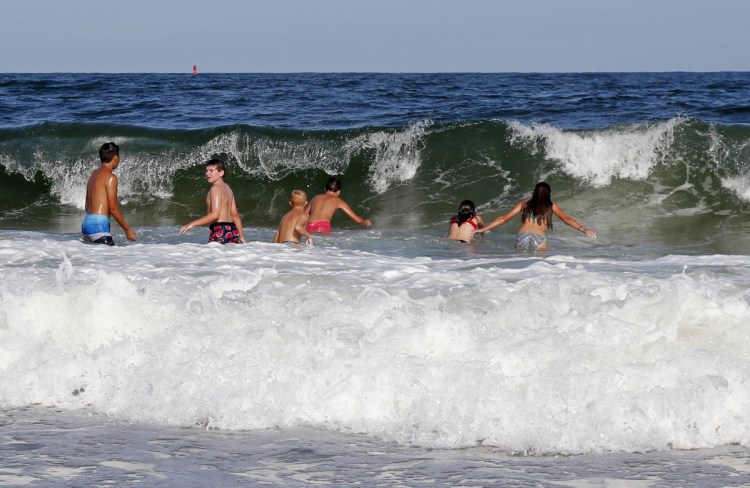 Swimmers dive into a wave at Seabrook Beach on Monday in Seabrook, New Hampshire. Authorities say two swimmers caught in riptides on Sunday have died. Rip currents, sometimes referred to as riptides, are narrow channels of water that move as fast as 8 feet a second and occur at any beach with breaking waves. Anyone caught in them is advised to swim parallel to shore to escape their pull.