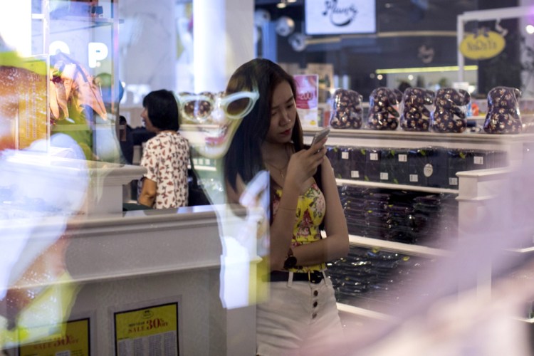 A shopper looks at a smartphone at a mall in Bangkok, Thailand, in June. By 2020, more than half of the world's population will be "middle class," one researcher says.