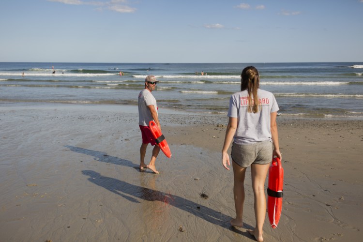 Lifeguard captain Christopher Lessard and lifeguard Mira Kuni walk down to the water at Fortunes Rocks Beach in Biddeford on Thursday.