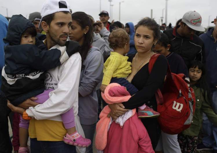 Jorge Gonzales and his wife, Kenia, carrying their boys, wait in line for breakfast, after crossing the border into Peru on Friday before the deadline for new regulations that demand passports from migrants.
