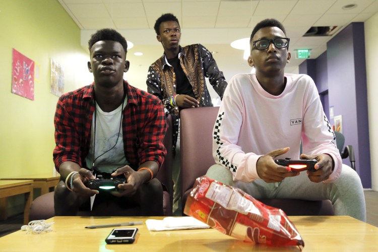 Paul Kana, left, plays EA Sports' FIFA video game against Abdirahim Mohamed in Portland, while Philip Kana assumes the role of referee. The average teen spends nine hours a day looking at a screen, a 2015 Common Sense Media survey found. Staff photo by Ben McCanna