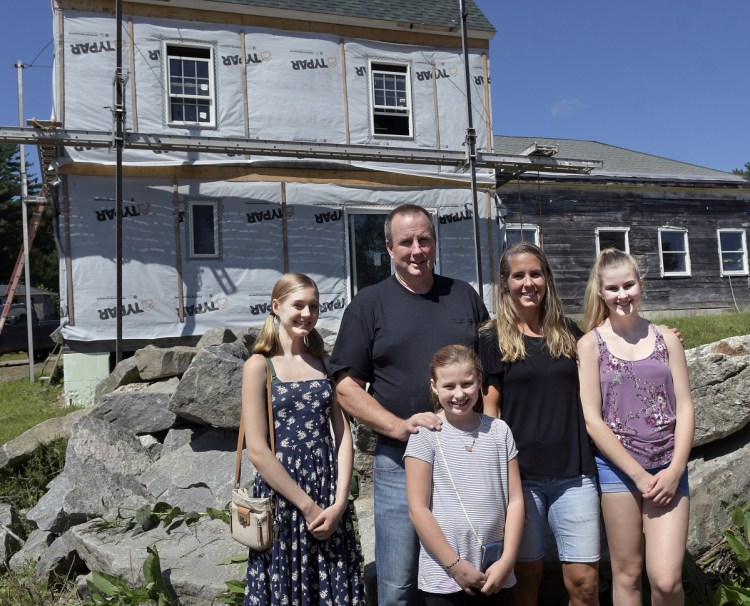 John Pagurko stands with his wife, Melanie, and their daughters, from left, Calista, Christina and Shae-Lynn on Thursday outside the home they are rebuilding in Whitefield following a destructive fire last year. Church and community volunteers are helping with both the building and the fundraising.