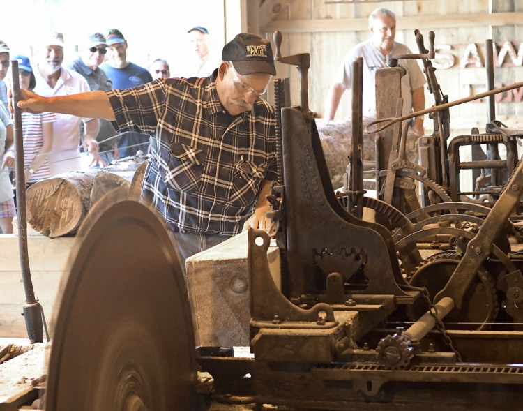 Bob Brann, left, and Jim Hawkes cut a log Sunday at the sawmill recently reassembled at the Windsor Fairgrounds.