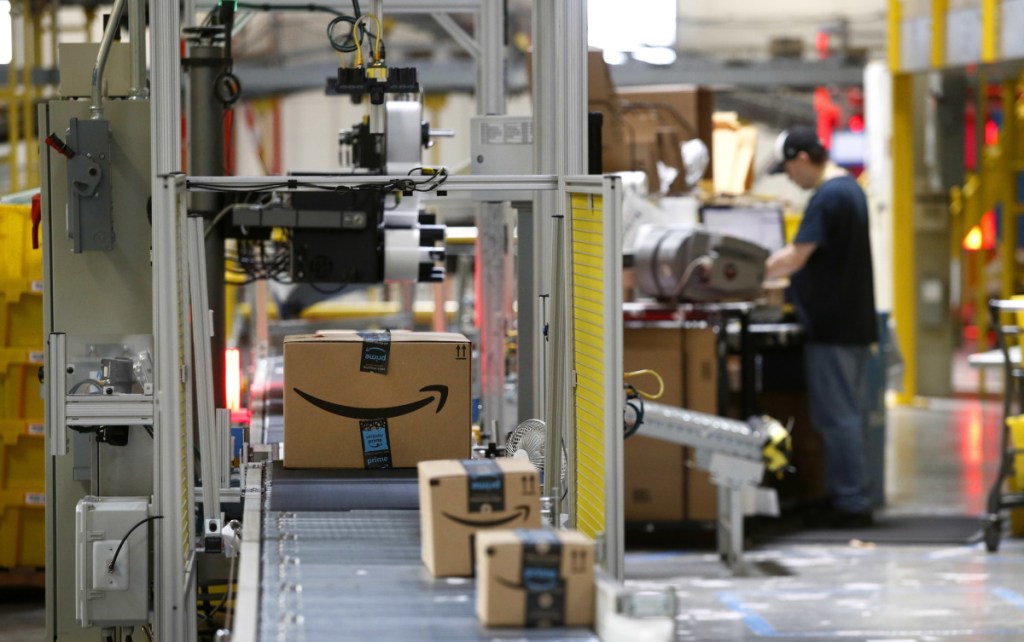 A machine scans packages at an Amazon fulfillment center in Baltimore. Amazon is paying workers to defend the company on Twitter, reassuring critics that they make a living wage and are allowed to take bathroom breaks. One worker tweeted: "We are totally happy working for an amazing company."