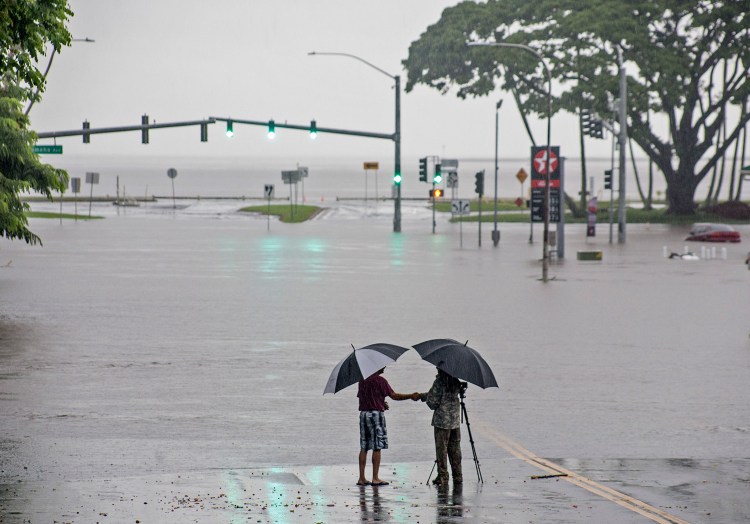 People stand near flood waters from Hurricane Lane on Thursday in Hilo, Hawaii. The storm dumped nearly 20 inches of rain in 24 hours as residents stocked up on supplies and tried to protect their homes from the state's first hurricane since 1992.