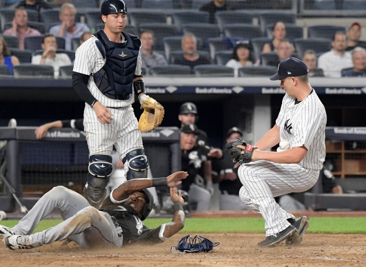 Chicago White Sox runner Tim Anderson, bottom left, scores on a wild pitch as New York Yankees pitcher A.J. Cole, right, cannot handle the throw from catcher Kyle Higashioka, top left, during the ninth inning on Monday at Yankee Stadium in New York. 