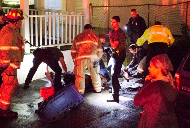 Rescue personnel tend to two people who fell from a third-story porch on Pierce Street in Lewiston on Wednesday night.