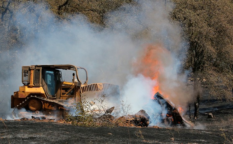 A Cal Fire bulldozer pushes through a mound of burning vegetation in Grass Valley, Calif. on Wednesday.