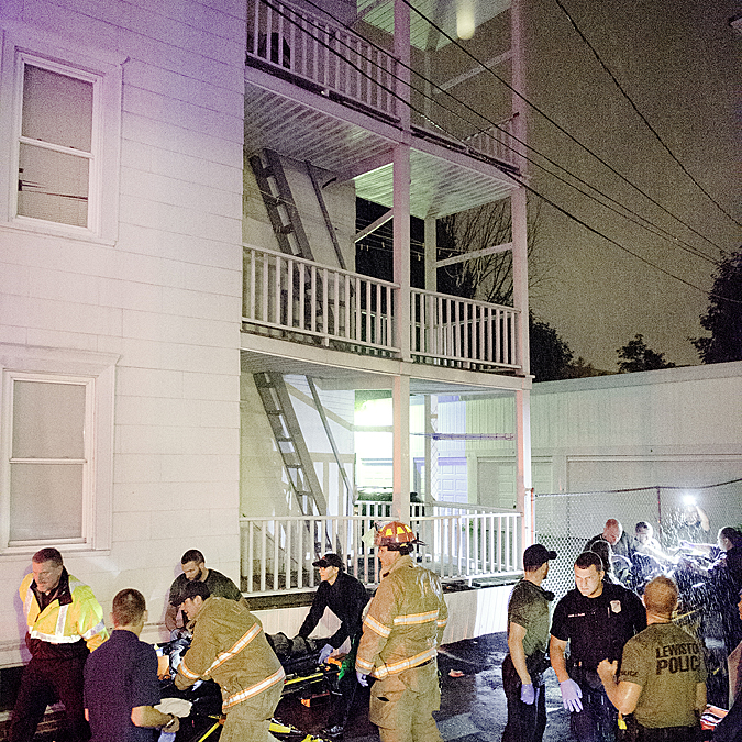 Two people are taken to an ambulance after falling of of a third story porch on Pierce Street in Lewiston on Wednesday night. The railing above gave way. 