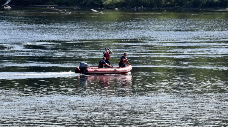 Skowhegan Fire Capt. Rick Caldwell, front, scans the Kennebec River with two other firefighters searching for the driver of a vehicle that crashed off Water Street early Sunday morning. Police say the man then jumped out of the vehicle and climbed down a steep embankment at the rivers edge. Caldwell said by mid-afternoon that the search was called off.