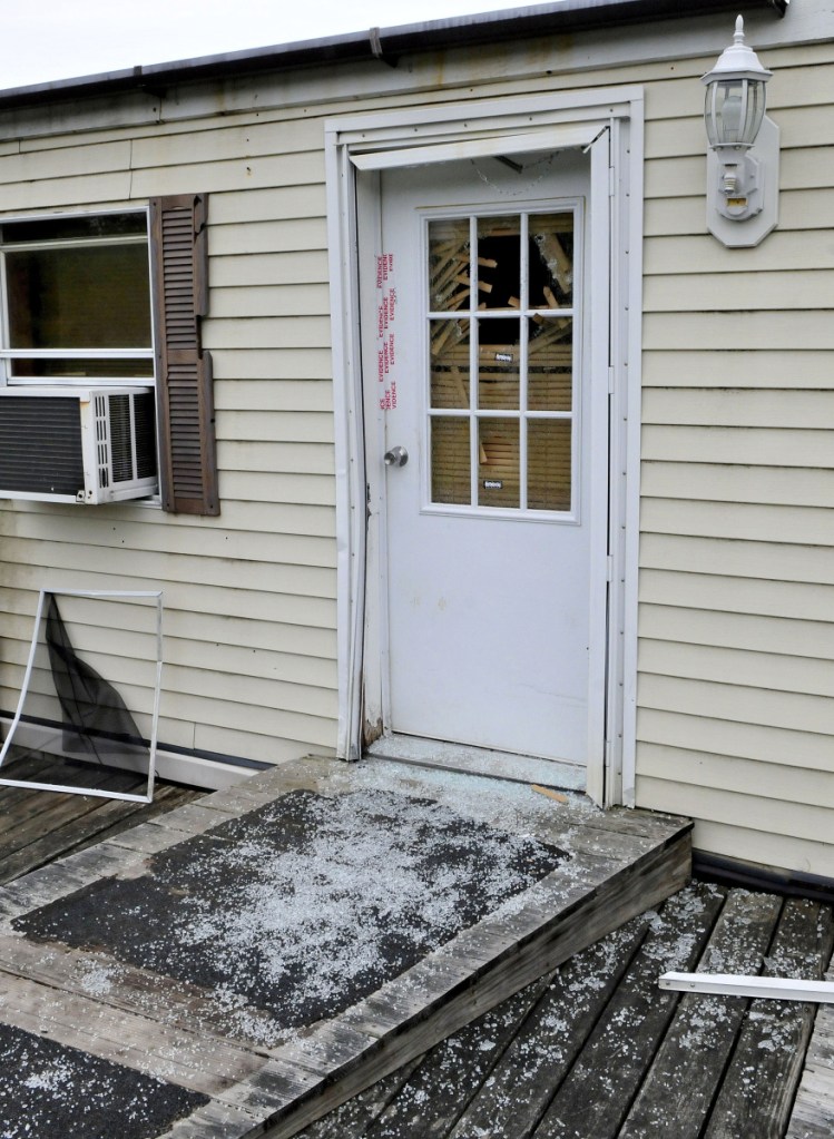 Glass from a shattered window in a door that is sealed with police evidence tape is seen at the front entrance to a mobile home at 1003 Oakland Road in Belgrade on May 22, 2017. Homeowner Roger Bubar died in a police officer-related shooting on May 19, 2017. His son Scott Bubar is standing trial on a charge of attempted murder of a police officer.