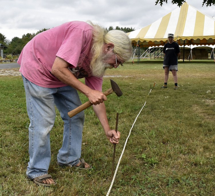 Ernie Glabau, a vendor and agriculture coordinator for the Common Ground Country Fair, stakes borders on Tuesday for a tent that will include his Entwood Bonsai tree booth while getting ready for the three-day fair in Unity that begins Friday.