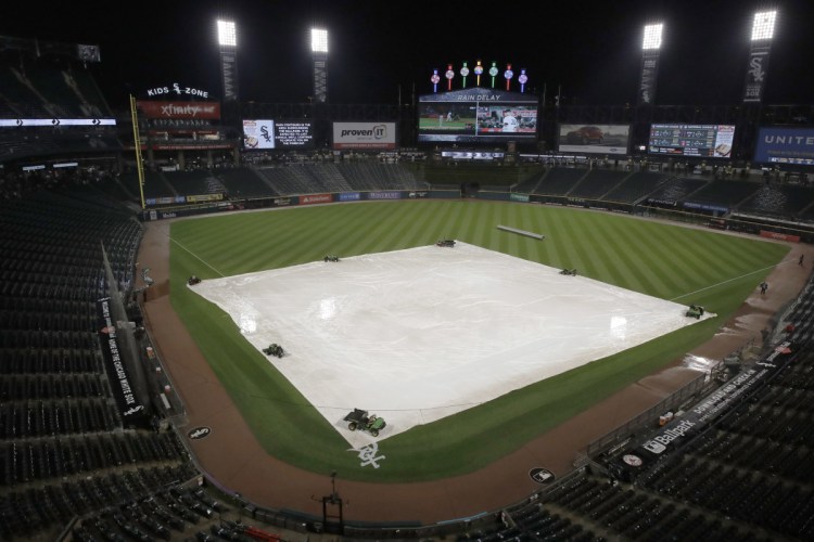 A tarp covers the infield as baseball fans wait out a rain delay during a baseball game between the Boston Red Sox and the Chicago White Sox on Friday night in Chicago. The delay lasted 2 hours and 9 minutes.