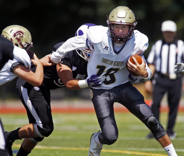 Thornton Academy quarterback Kobe Gaudette tries to shed a defender Saturday against Deering at Fitzpatrick Stadium. The Golden Trojans started their season with a 70-0 victory.