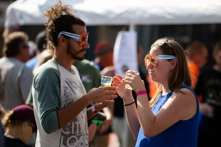 Chance Gonyer of Cornville and Leah Agren of Norridgewock share sips of brew samples at the Skowhegan Craft Brew Festival on Saturday. A few were walking around the festival Saturday afternoon while wearing pretzel glasses.