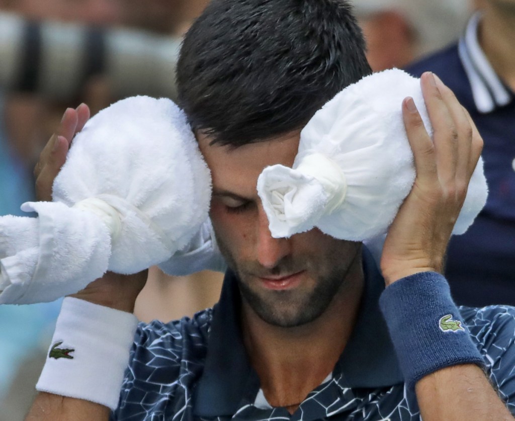 Novak Djokovic puts an ice towel around his head during a changeover against Joao Sousa during their fourth-round match on Monday. Djokovic won 6-3, 6-4, 6-3.