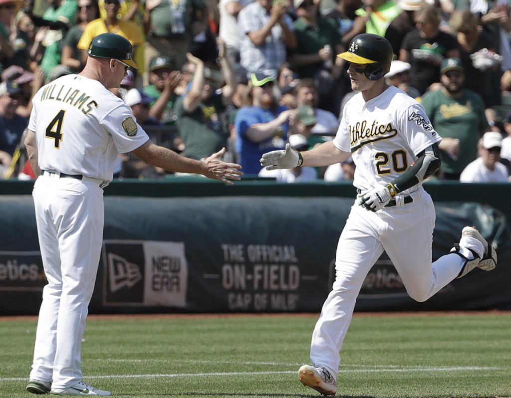 Mark Canha of the Athletics, right, is congratulated by third-base coach Matt Williams after hitting a solo home run against the Yankees during Oakland's 6-3 victory at home on Monday.