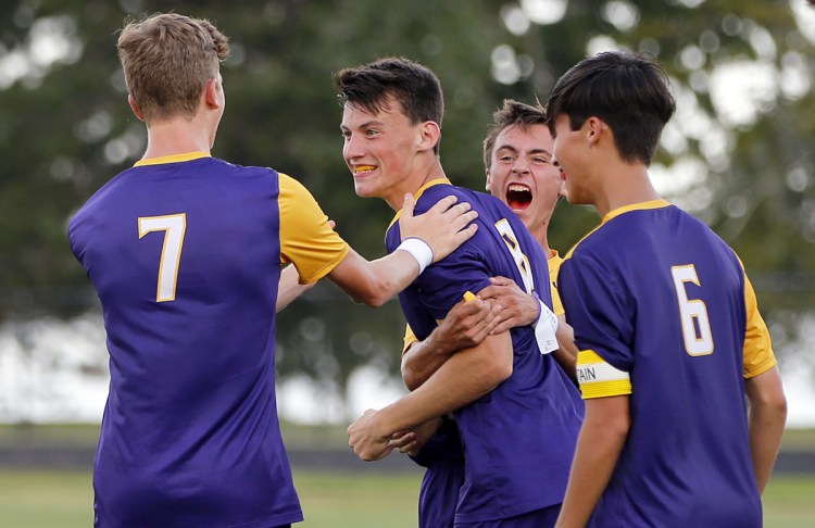 Teammates surround Owen Burke, who scored the winning goal with just over 11 minutes left in a boys' soccer game Tuesday in Portland. The Stags scored twice in the second half to top Falmouth, 2-1.