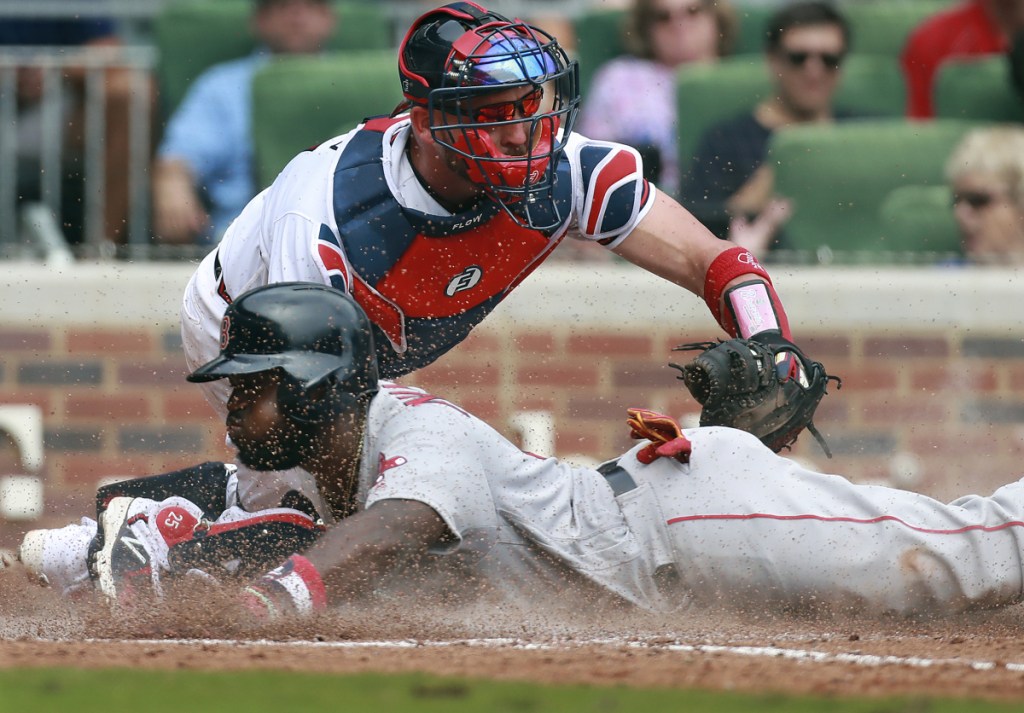 Boston's Brandon Phillips slides home safely to score past Atlanta Braves catcher Tyler Flowers during the eighth inning Wednesday in Atlanta. Phillips then hit the game-winning home run in the ninth inning as Boston won, 9-8.