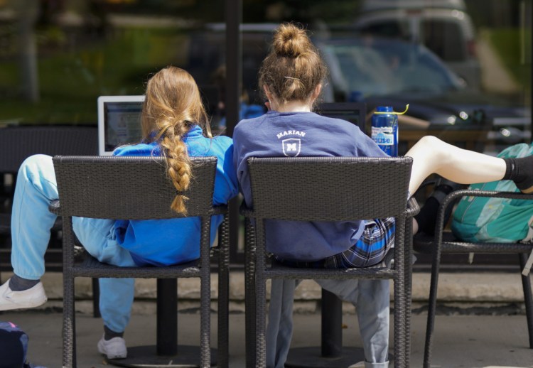 Two customers relax outside a Starbucks store in Omaha, Neb. Researchers say it appears that neighborhoods chosen by Starbucks for new stores are often poised to see a jump in housing prices.