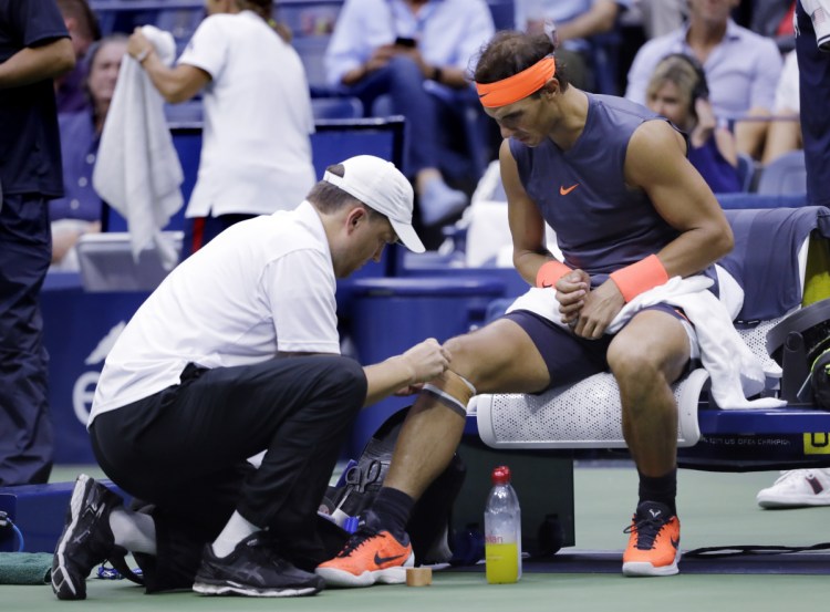 Rafael Nadal is treated by a trainer during a change over against Juan Martin del Potro during the semifinals of the U.S. Open on Friday in New York. Nadal retired after two sets because of a sore right knee.