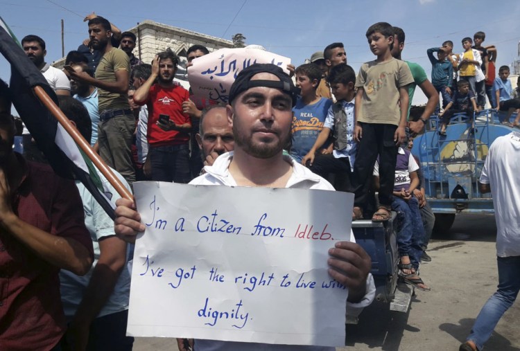 A protester holds a placard, in Harim, Syria, on Friday. The rallies were part of a day of protests against Syrian President Bashar Assad and his troops' imminent offensive against Idlib, the last bastion of rebels in Syria.