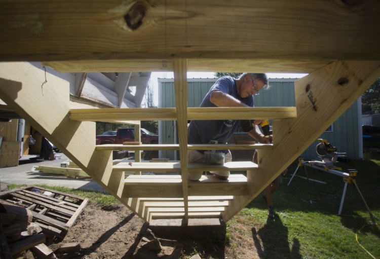 John Lichter, a volunteer with Harpswell Aging at Home, installs exterior stairs at the home of Steve Taylor, 83, on Aug. 29. In recent years, more than 100 Maine communities have established Aging in Place initiatives to cover what they see as a state remiss to live up to its responsibilities.