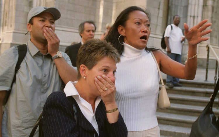 People in front of New York's St. Patrick's Cathedral react with horror as they look down Fifth Avenue toward the World Trade Center towers after planes crashed into their upper floors on Sept. 11, 2001.