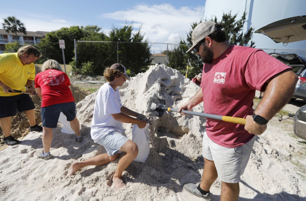 Walker Townsend, right, fills a sand bag while Dalton Trout, center, holds the bag at the Isle of Palms, S.C., municipal lot, where the city was giving away sand in preparation for Hurricane Florence.