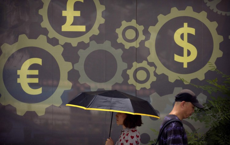 People walk past a mural displaying world currency symbols on the outside of a bank in Beijing. Washington has invited Beijing to hold new talks on their escalating tariff dispute, China said Thursday.