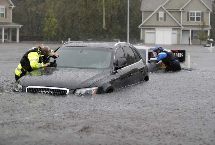 Members of the North Carolina Task Force urban search and rescue team check cars in a flooded neighborhood in Fayetteville, N.C., on Sunday, looking for residents as Florence continued to dump more than 30 inches of rain in spots.