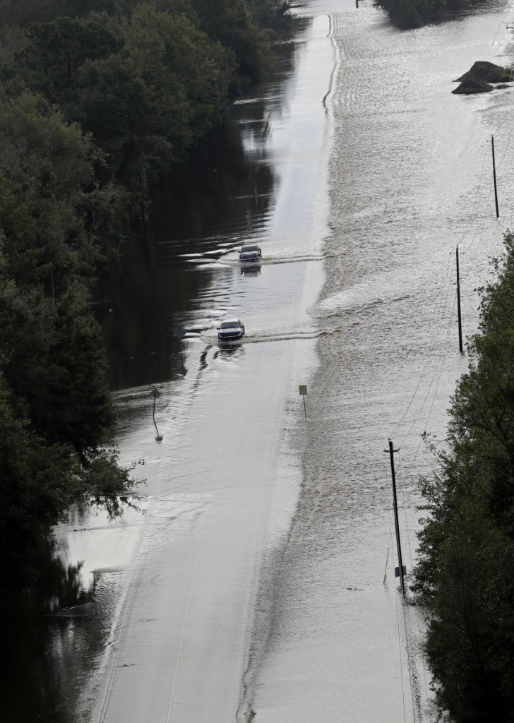 Cars make their way down a road overtopped by rushing floodwater from Hurricane Florence in Dillon, S.C., on Monday. Navigation apps like Waze are trying to help motorists avoid hurricane flooding, but local authorities say people shouldn't rely on them.