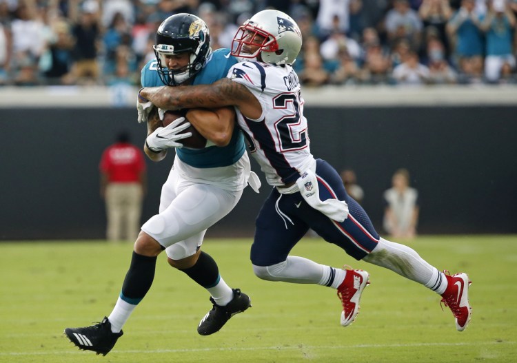 Safety Patrick Chung, right, tackles Jacksonville's James O'Shaughnessy on Sunday. Chung suffered an apparent head injury and was sent off the field by officials, but came back one play later. He did not play the second half.