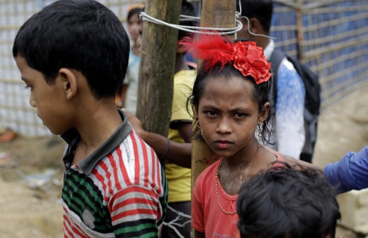Muslim Rohingya children driven out of Myanmar by ethnic cleansing wait at the entrance to Jamtoli refugee camp in Bangladesh. War, famine and government persecution have displaced over 68 million worldwide.