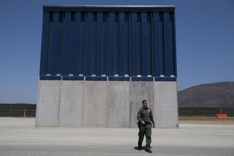 Border Patrol Public Affairs Officer Vincent Pirro looks at border wall prototypes that stand in the San Diego sector of the border wall in April.