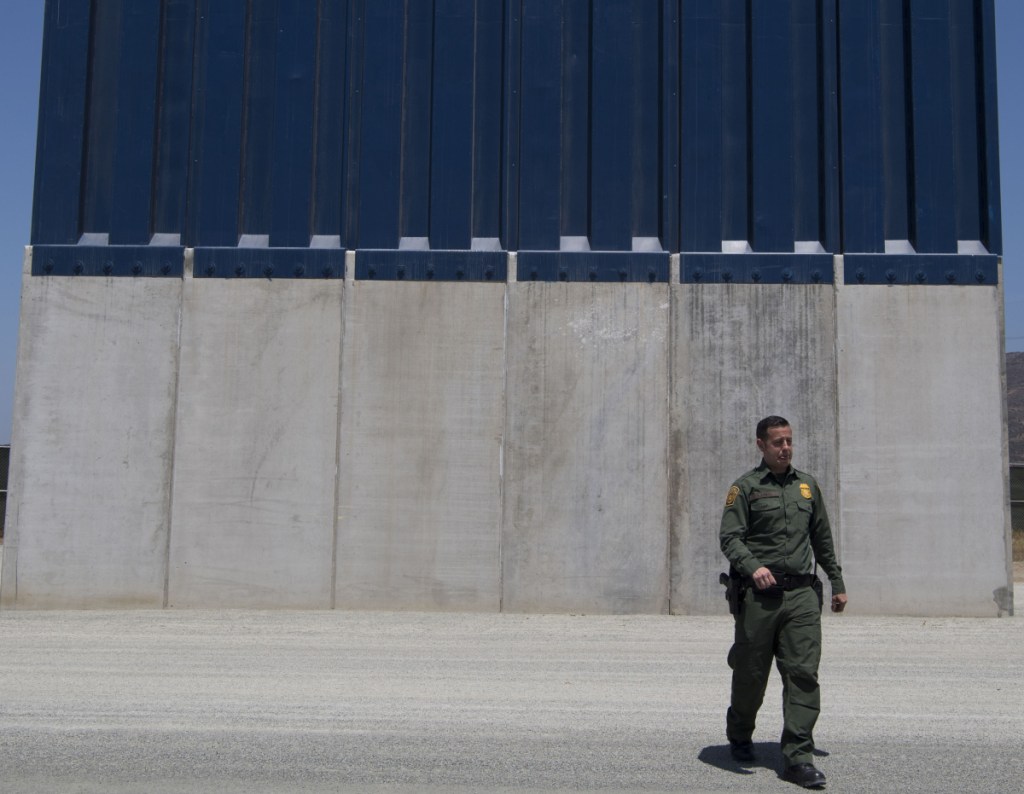 A Border Patrol official inspects border wall prototypes in the San Diego area last April.