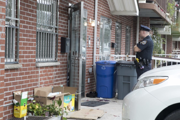 A police officer stands guard at the house were five people, including three infants, were stabbed on Friday in New York.