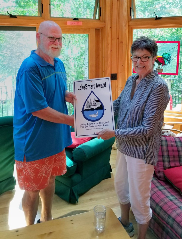 Maggie Shannon, director of the Maine Lakes Society, presents the LakeSmart Award to Earl Sasser of Pleasant Lake in Otisfield. She is a determined protector of water quality in Maine lakes.
