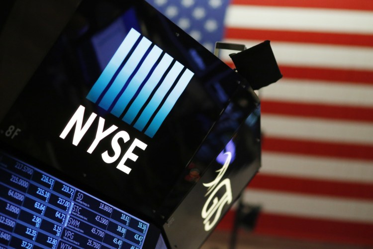 A New York Stock Exchange sign above the trading floor. The stock market made small gains Thursday, but smaller firms fell, and slipping interest rates led to bank losses.