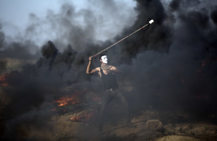 A Palestinian protester hurls stones at Israeli troops during a protest at the Gaza Strip's border with Israel on Friday.