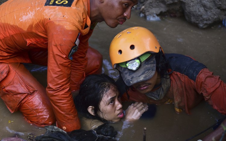 Rescuers try to help 15-year-old earthquake victim Nurul Istikharah from her damaged house following an earthquake and tsunami in Palu, central Sulawesi, Indonesia, on Sunday. Rescuers were scrambling to find victims trapped in collapsed buildings where voices could be heard.